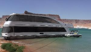 Large houseboat anchored on shoreline of Lake Powell with smaller vessel attached.