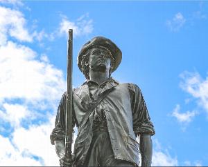 Picture of the Minute Man Statue against a blue sky with white clouds.