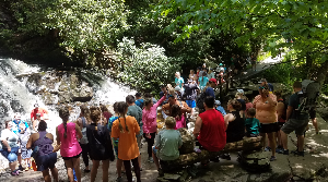 Photo of visitors gathering at Laurel Falls. Some are seated on a wooden bench, most are standing, some pose for a picture in front of the upper falls.
