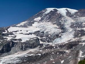 Photo of Mount Rainier, a glaciated volcano with blue skies above.