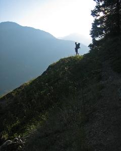 The silhouette of a backpacker is outlined against a smoky sky in mountainous terrain.
NPS photo/Bender