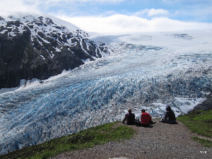 Three people sit on the side of the trail, overlooking Exit Glacier. NPS photo, 2010.