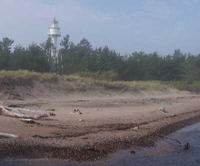 image along the coastline with the beach, trees, and lighthouse