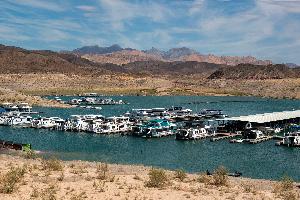 This is a photo of the Callville Bay Marina at Lake Mead National Recreation area. There are several boats in the water at a marina with desert landscape in the foreground and desert mountain landscape in the background.