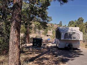 Photo of a pop-up camper at a campsite in Juniper Campground with bear locker, camp chairs, and picnic table.