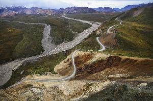 Image shows an aerial view of the Polychrome area, with the sinuous Denali National Park road and the braided river below.