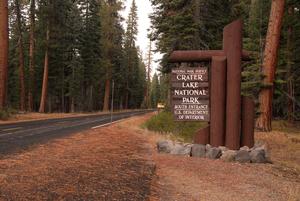 When you enter Crater Lake National Park using the Southern Entrance on Highway 62, the land to the west of the highway for the first 2.4 miles is within the West Panhandle Forest Restoration Project area. The photo shows the Crater Lake entrance sign at the south entrance to the park and forest on either side of Highway 62.