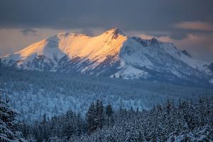 Sunlight hits the side of a snow-covered mountain in Yellowstone National Park