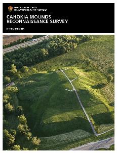 An image of the cover of the Cahokia Mounds Reconnaissance Survey, dated December 2016. On the cover is an aerial image of Monks Mound, the largest earthen mound in North America, covered in grass in the morning sunlight. The stairs and path to the top of the mound are visible. In the foreground, a small part of Colinsville Road is visible, and behind the mound, beyond a stand of trees, Interstate 55/70 is visible.