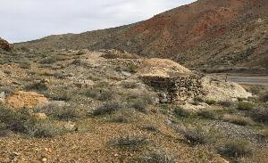 Photograph of the Starr Mill Site. Waste piles and stone retaining walls are in the center and Emigrant Canyon Road is in the background on the right.