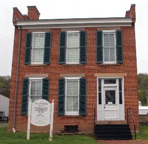 Front view of the John P. Parker House and Museum, a 2 story red brick side gable house with stone lintels and sills and green window shutters.