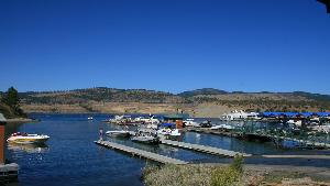 An image of boats and docks in a blue lake with rolling hills and blue sky in the background.