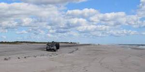 A fisherman and his vehicle on the ocean beach.