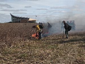 Firefighters starting a prescribed fire at Homestead National Monument of America. In the background is the Homestead Heritage Center.
